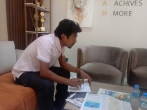 Antor Hossain reviewing documents at the BGBA (Bangladesh Garment Buying House Association) office, surrounded by newspapers and industry materials.