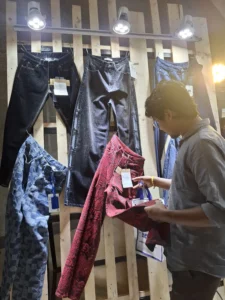 Apparel expert examining a red pair of textured pants at a denim or fashion trade show in Dhaka.