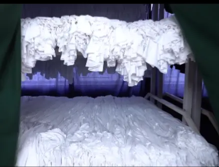 Stacks of white fabric prepared for sustainable apparel production.