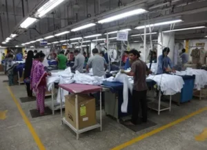 Workers efficiently ironing garments at designated stations in a well-organized production facility. -Antor