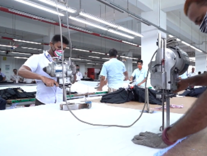 Garment workers cutting layered fabric with straight knife machines in a Bangladesh woven and denim factory